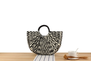 Detail of two-tone paper rope woven tote with radial texture on a wooden surface