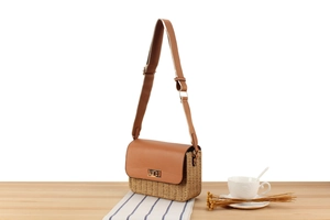 Close-up of paper rope woven bag featuring brown leather flap and golden rotary metal lock