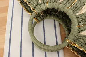 Detailed close-up of green and beige paper rope weave bag with metallic gold thread accents