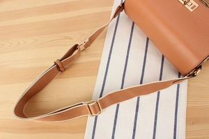 Detail of woven paper straw bag featuring adjustable shoulder strap and golden buckle