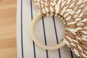 Detail of hand-woven paper rope bag with round handle in beige and brown color tones