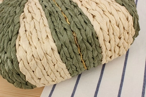 Macro detail of hand-woven paper straw bag with green stripes and gold silk thread