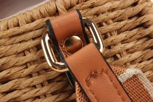 Macro detail of leather strap with gold metal buckle on woven paper straw beach bag
