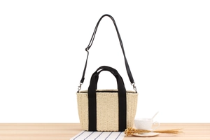Gros plan sur la texture du sac en papier tissé beige avec poignées et bandoulière