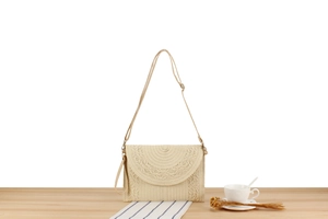 Detail of hand-woven straw crossbody bag with adjustable strap and semi-circular pattern