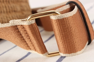 Detail of premium paper rope woven bag strap with golden metal buckle and brown leather joinery