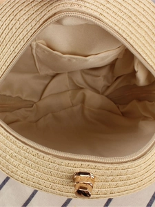 Top view of woven round straw bag showing interior fabric lining and metal zipper closure