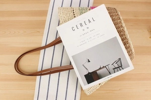 Detailed close-up of large straw tote bag with beige paper rope weave and leather handles
