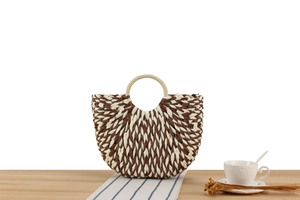 Detailed view of woven straw tote featuring dual-tone wave pattern and circular top handles
