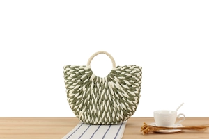Detail of olive and beige woven straw bag with dual-tone semi-circle pattern