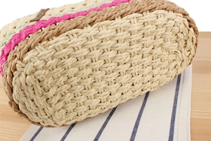 Detailed close-up of the woven base of a colorful paper straw tote bag for vacation