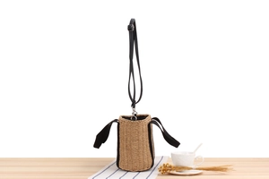 Détail d'un sac seau en paille avec poignées en oreilles de lapin noires sur bois