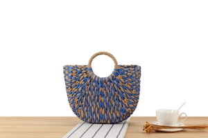 Detailed close-up of woven semicircular beach bag in blue and brown straw patterns