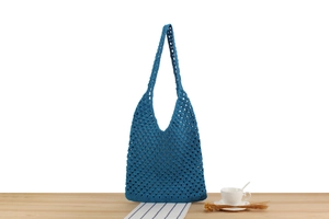 Gros plan d'un sac cabas tissé bleu foncé ajouré posé sur une surface en bois