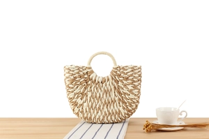 Detail view of a semi-circular woven straw handbag with bicolored paper rope textures