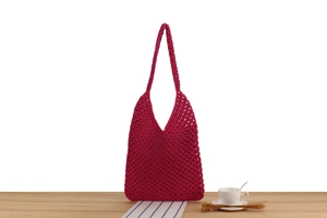 Gros plan du sac à bandoulière en maille crochetée rose foncé avec détails tissés