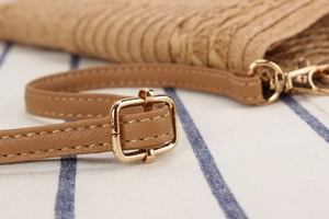 Macro shot of adjustable leather strap and polished gold hardware on woven bag
