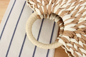 Detail of round handles and dual-tone woven paper rope texture on a beach tote bag