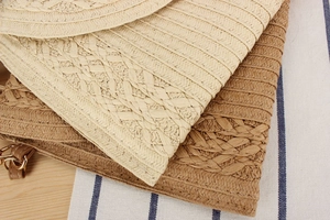 Detail of woven straw envelope bags showing beige and brown texture with metal rings