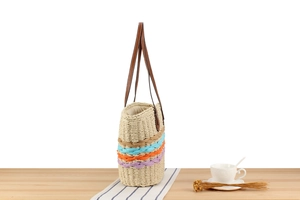 Close-up of hollow straw woven tote bag with colorful patchwork and leather handles
