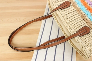 Detail of paper straw tote with brown leather handles and colorful braided trim accents