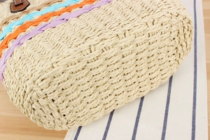 Detailed close-up of woven paper rope texture and colorful stripes on a beige beach bag
