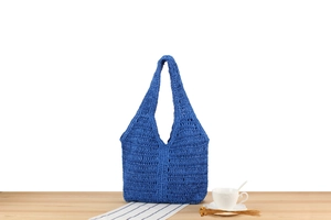 Détail du sac cabas évidé bleu roi en corde de coton sur une table en bois