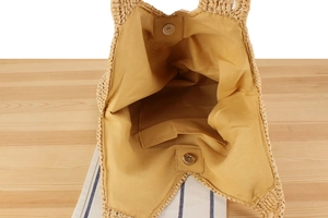 Détail du sac en paille tressée avec fermeture magnétique et doublure en tissu jaune clair