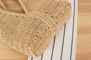 Gros plan détaillé sur la texture tressée à la main d'un grand sac bandoulière en paille