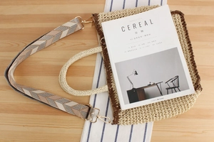 Detail of paper straw crossbody bag with geometric shoulder strap on wooden background
