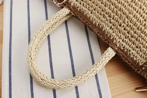 Close-up of dual-tone paper rope woven bag with golden metal rings and handles