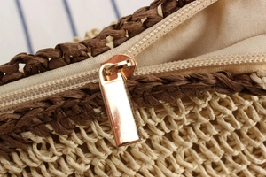 Detailed close-up of woven paper straw texture with metal zipper and fabric lining