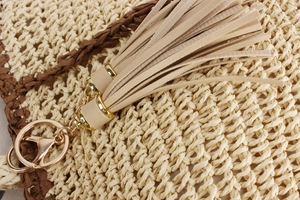 Detailed macro view of woven paper rope bag texture with beige leather tassels and gold ring