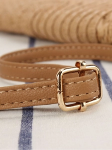 Brown leather strap with gold buckle and fine stitching on a woven straw bag