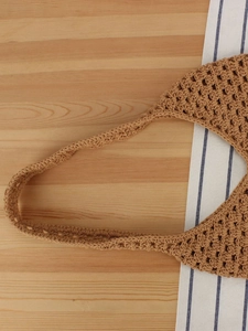 Sac à main en crochet kaki fait main avec motif ajouré sur fond en bois rustique