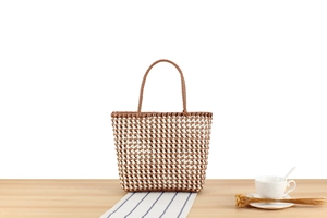 Détail du sac cabas tissé en PVC à carreaux avec poignées semi-circulaires sur table
