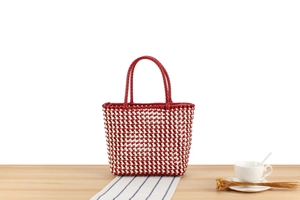 Détail du sac cabas tissé en PVC rouge et blanc montrant la texture sur bois