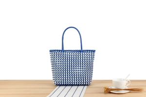 Détail de la texture d'un sac cabas tissé en PVC bleu et blanc sur bois