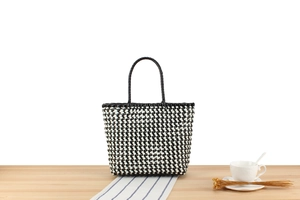 Détail d'un sac à main tissé à carreaux noirs et blancs avec anses rondes sur la table