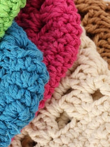 Gros plan de sacs en coton crochetés à la main dans de nombreuses nuances vives et variées