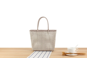 Détail du sac cabas en PVC tissé à la main avec texture à carreaux beige et taupe
