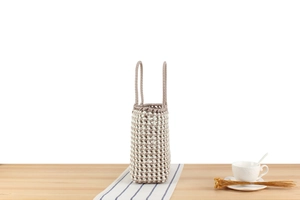 Détail d'un sac cabas tissé en PVC à damier sur table avec tasse à café décorative
