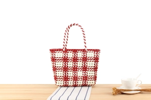 Close-up of red and white woven PVC tote bag on a wooden table for beach or shopping