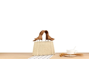 Detail of woven straw handbag with twisted brown leather handle and metal rings