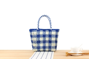 Detailed blue and white checkered woven tote bag placed on a wooden table for daily use
