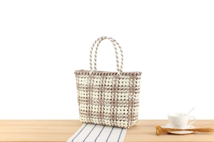 Macro detail of the checkered PVC woven tote bag on a wooden table with decor