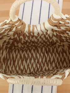 Handwoven straw beach bag with white and brown stripes and circular top handles