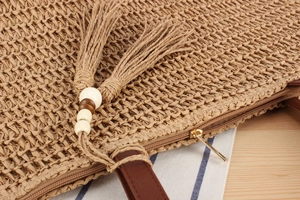 Detailed macro view of woven straw tote bag with decorative tassels and wooden beads
