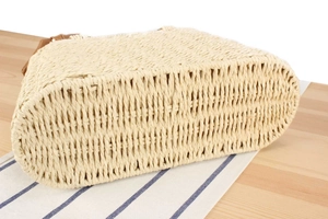 Close-up of natural straw weave bag with a flat oval bottom on a rustic wood surface