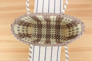 Top view of a woven brown and beige PVC tote showing spacious interior on a wooden table